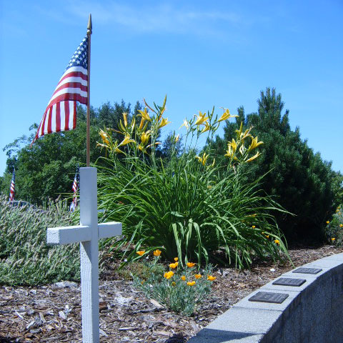 Image of Cross marker and American flag at Sylvan Cemetery.